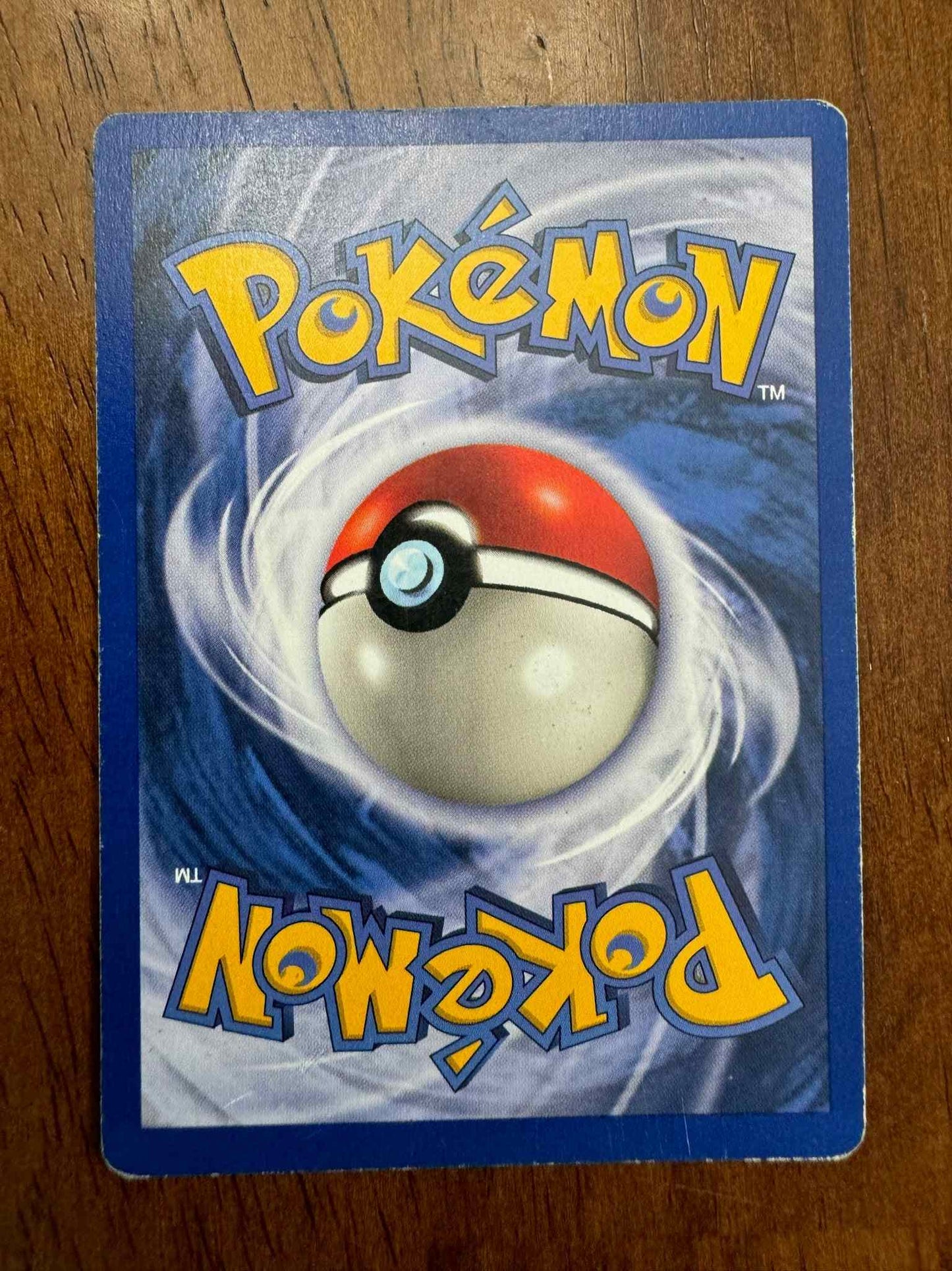 Pokémon Base Set #027/102 Farfetch'd collectible card on wooden background.