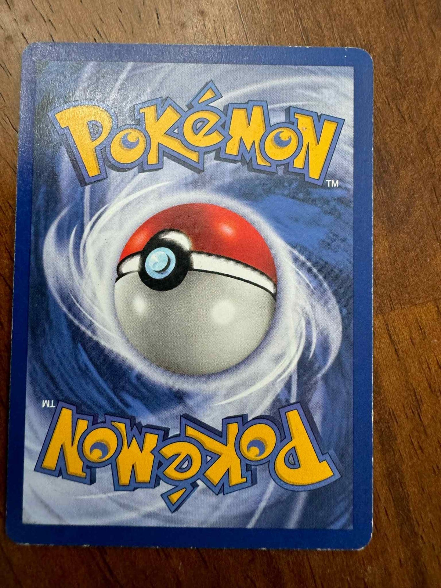 Fossil #27/62 Moltres Pokémon card back on wooden surface.
