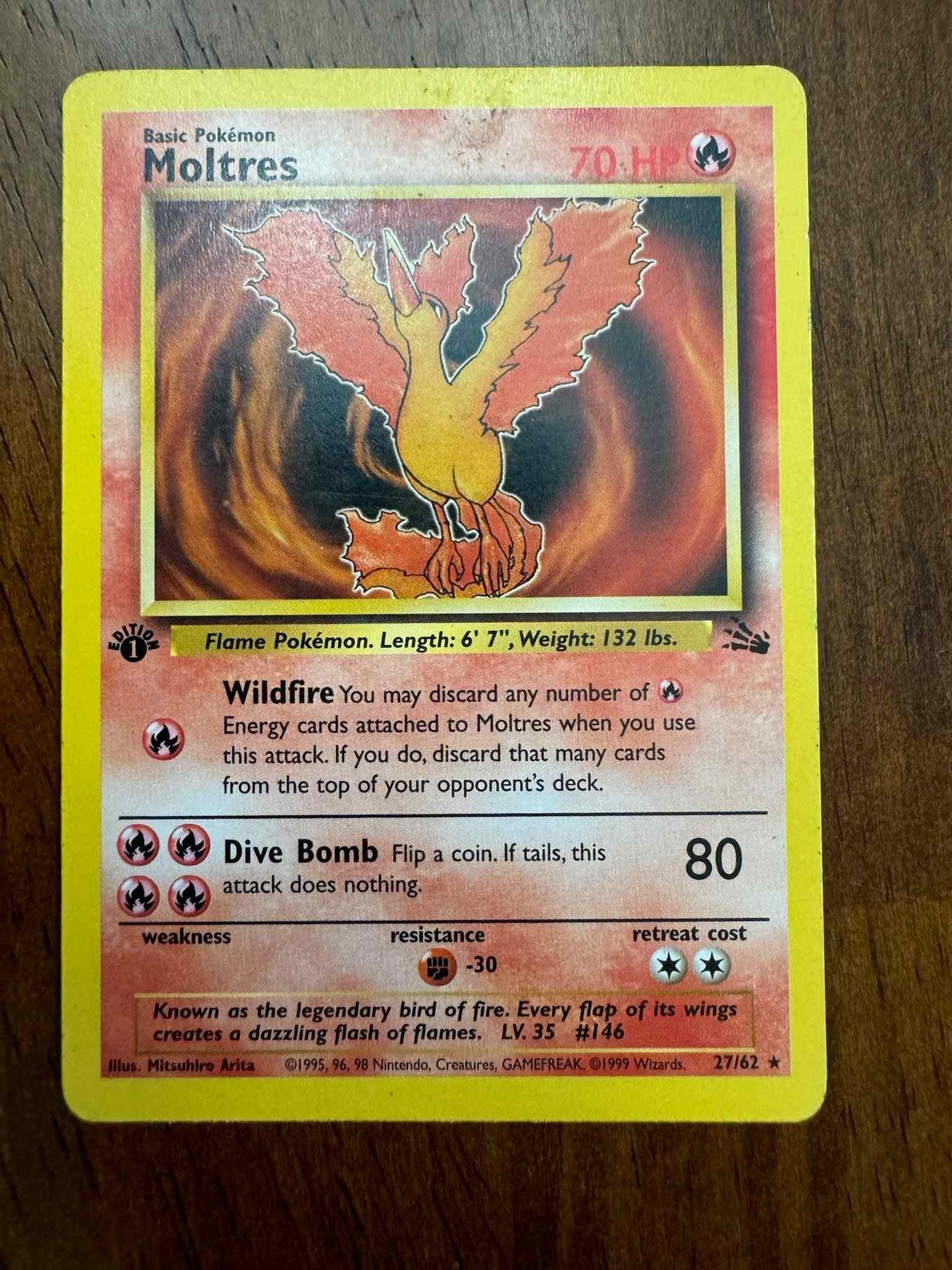 Fossil #27/62 Moltres collectible Pokémon card on wooden background.