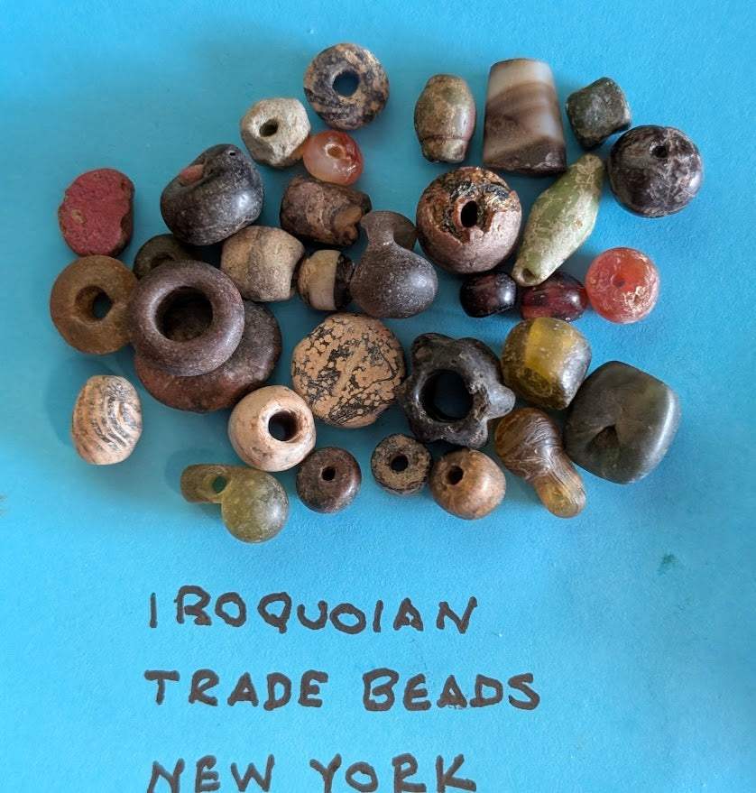 Assortment of authentic Iroquoian trade beads and pendants from New York region on blue background