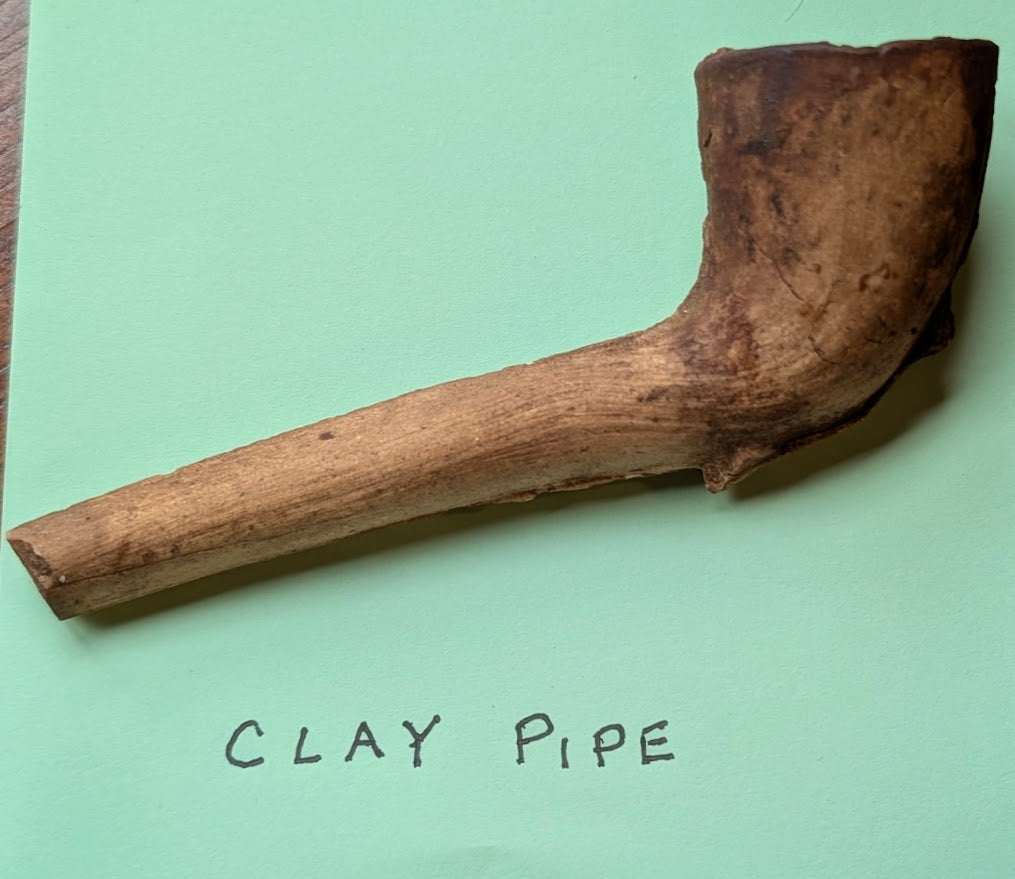 Antique clay tobacco pipe with long stem and rounded bowl from early American frontier era