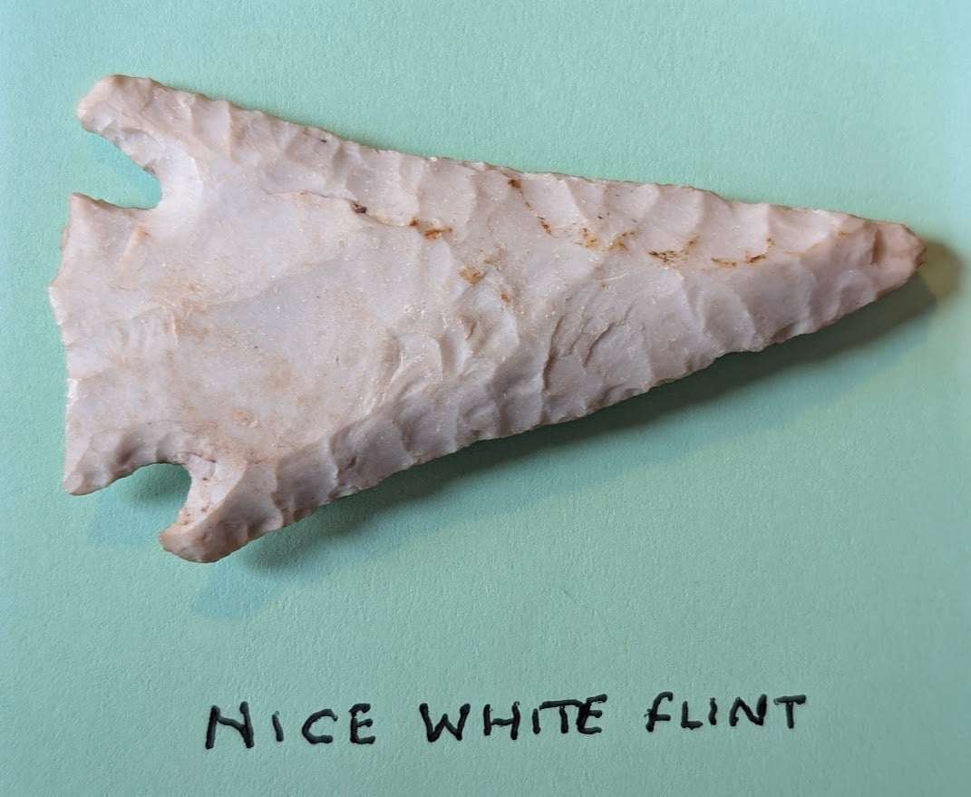 Large white flint Native American arrowhead with notched triangular point and detailed flaking patterns