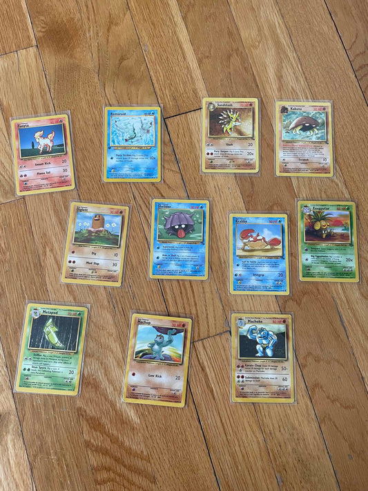 1995 Pokemon non-holo card lot featuring 11 unique cards on wooden floor.