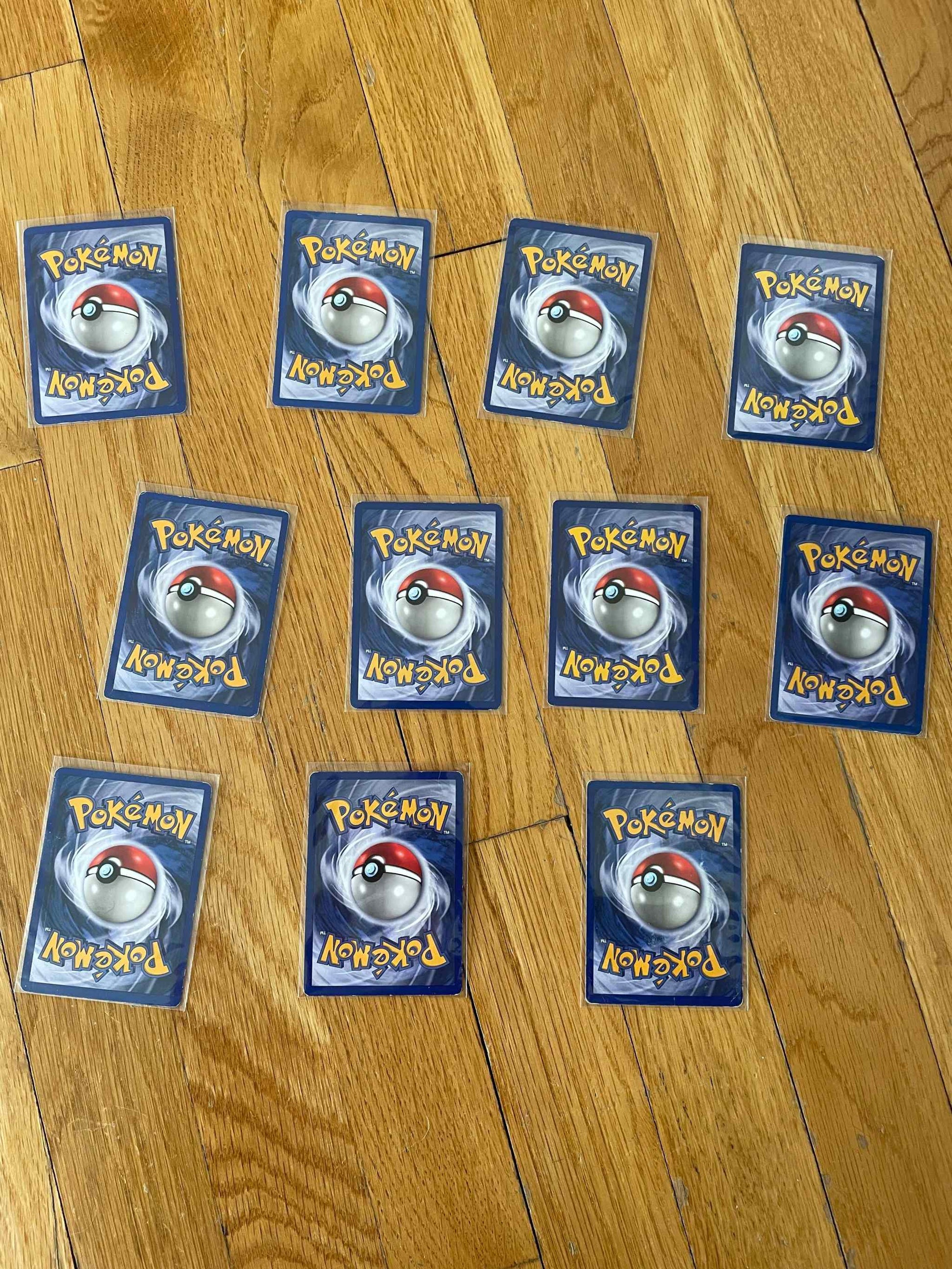 1995 non-holo Pokemon card lot, 11 unique vintage cards displayed on wood floor.