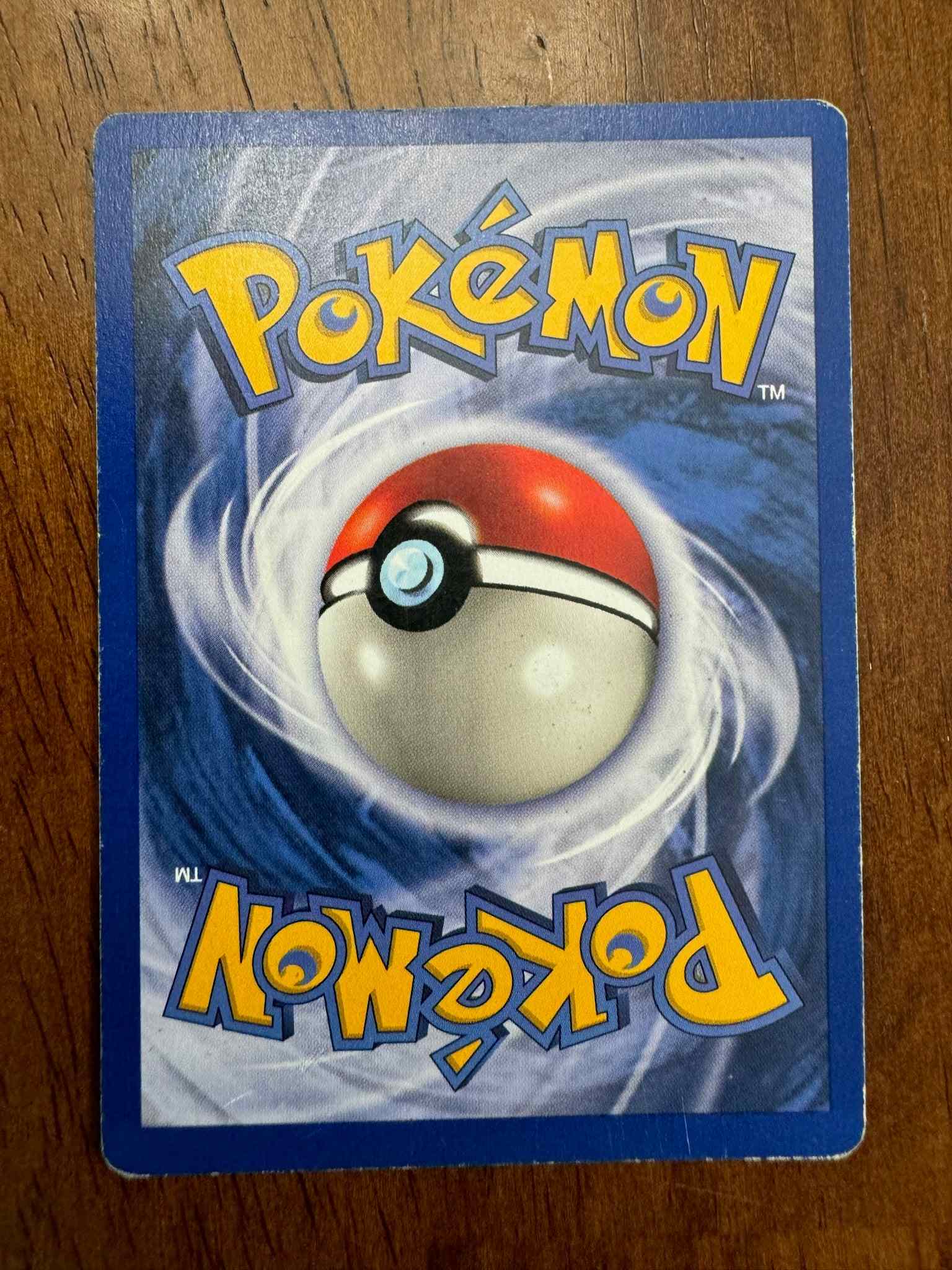 Pokémon Base Set #027/102 Farfetch'd collectible card on wooden background.