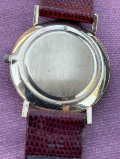 Vintage Lucien Piccard ultra slim 14k gold mechanical watch with leather strap on purple background.