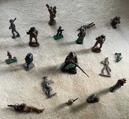 Lot of vintage cast toy combat military soldier figurines on display.