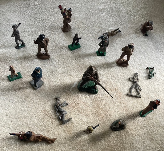 Lot of vintage cast toy combat military soldier figurines on display.
