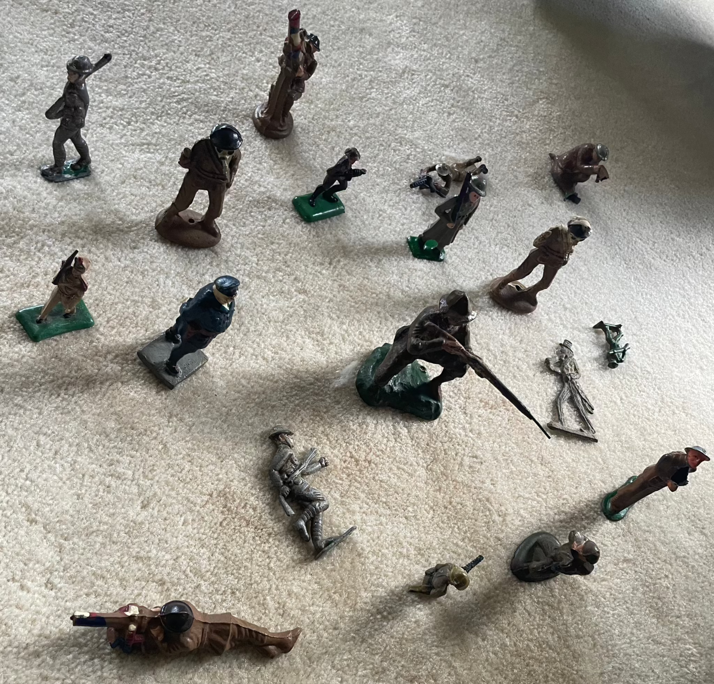 Lot of vintage cast toy combat military soldier figurines on display.