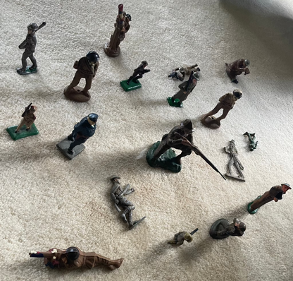 Lot of vintage cast toy combat military soldier figurines on display.