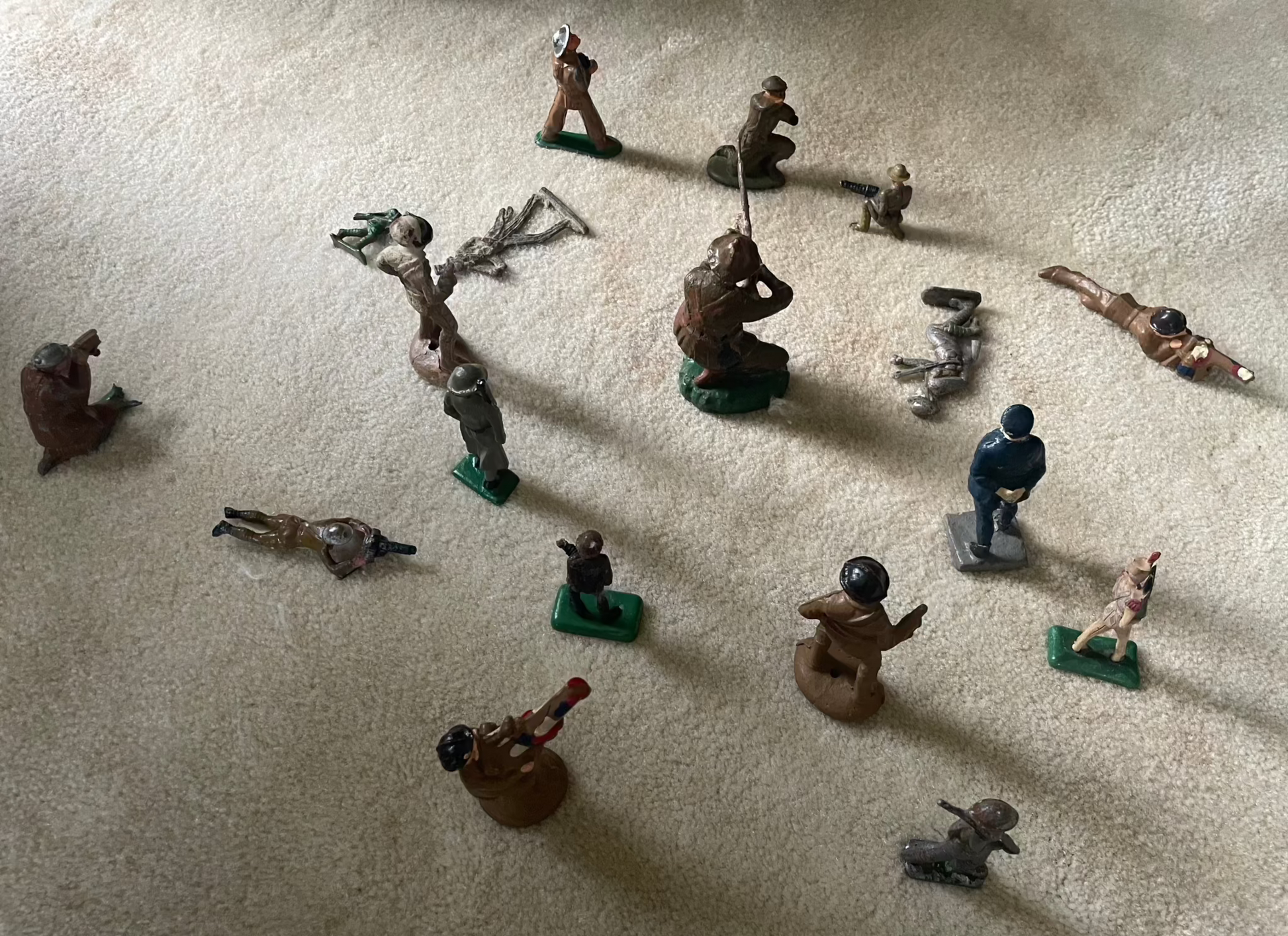 Lot of vintage cast toy combat military soldier figurines on display.