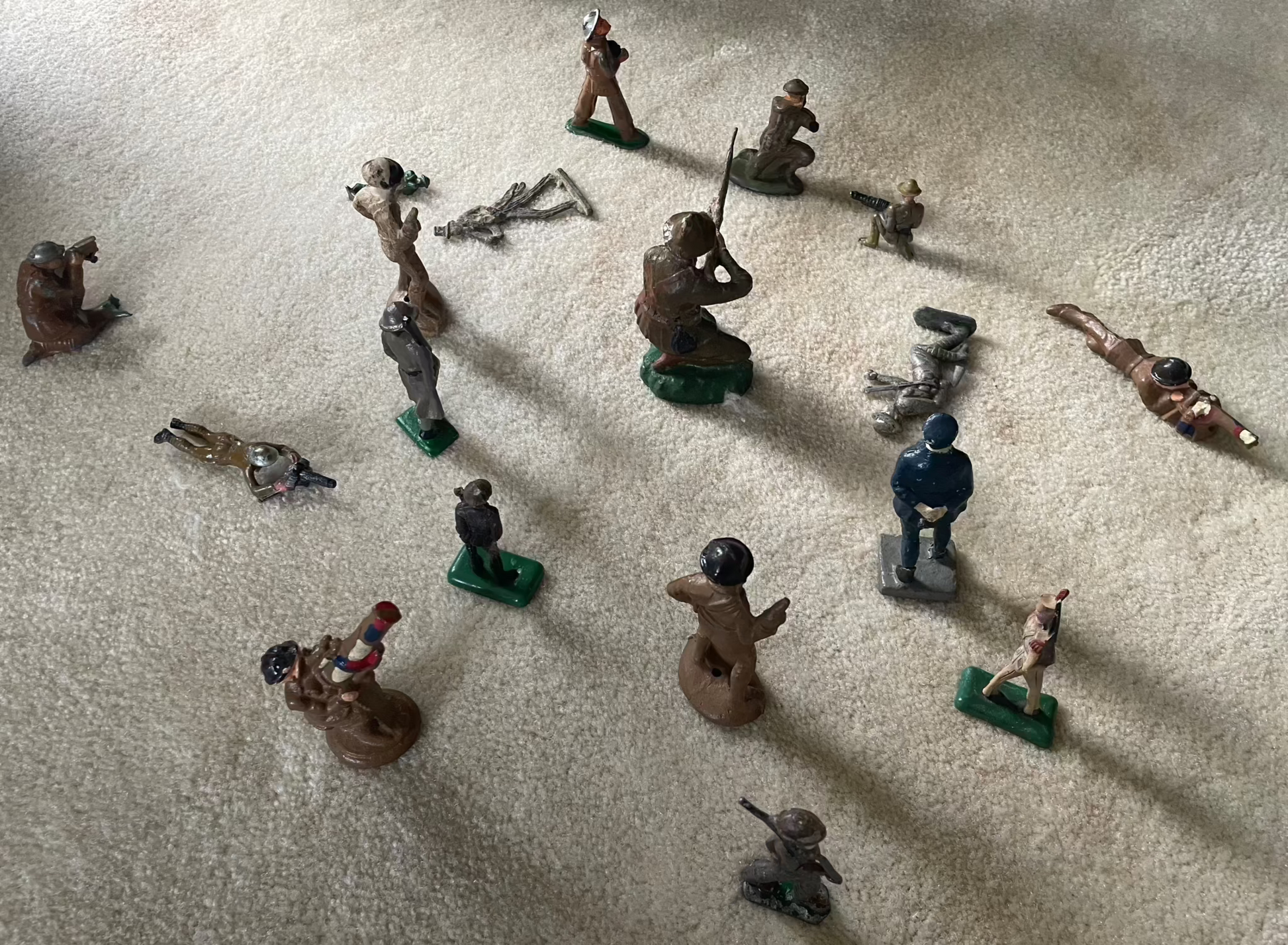 Vintage cast toy combat military soldier figurines on display carpet.