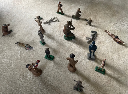 Vintage cast toy combat military soldier figurines on display carpet.