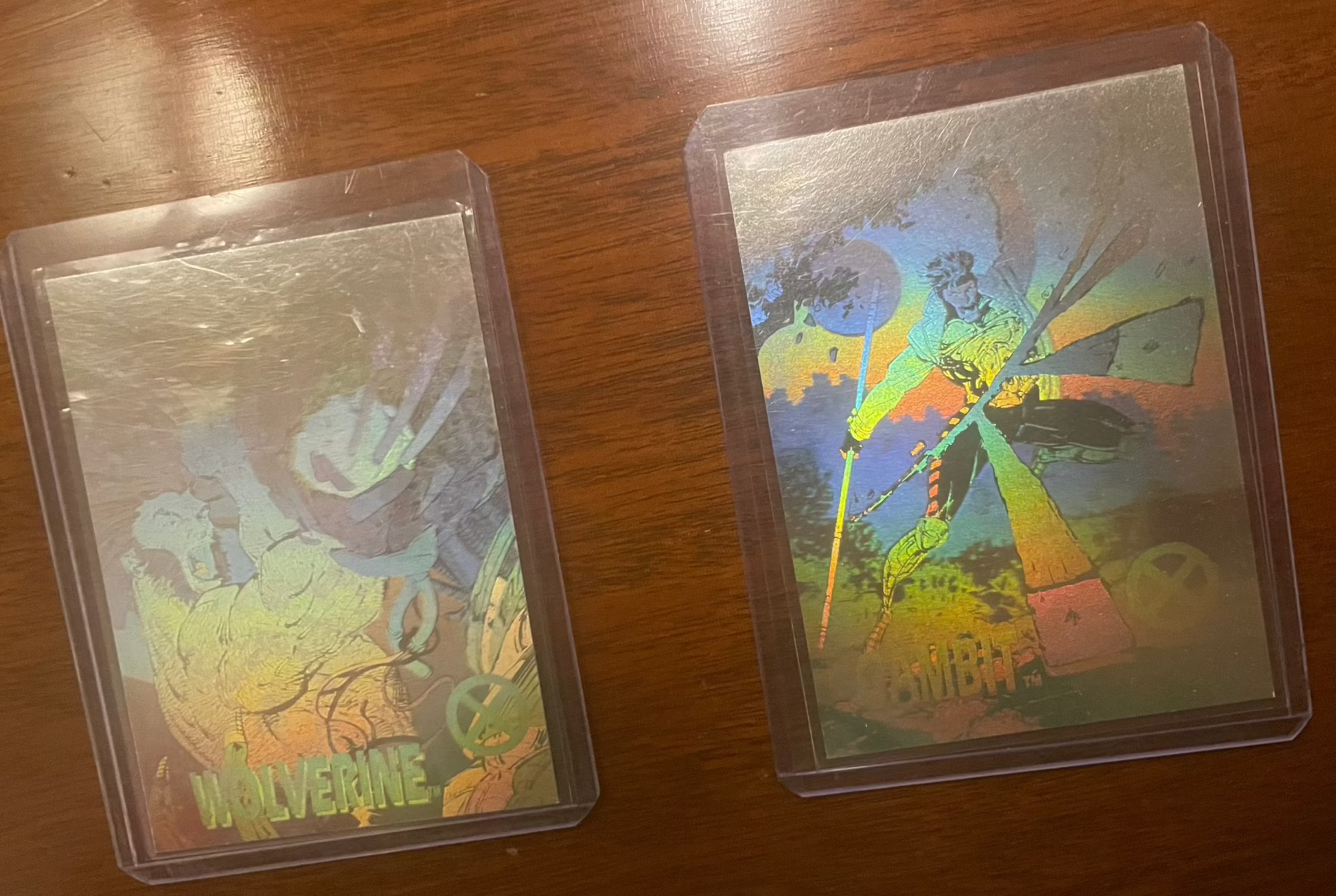 1992 Impel Marvel Universe Series 1 hologram cards featuring Wolverine and Gambit in protective sleeves on a wooden surface.