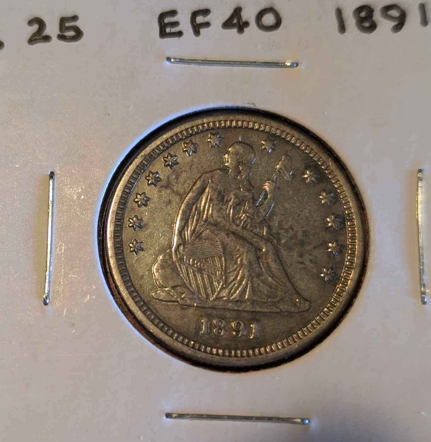 1891 Liberty Seated Quarter with "In God We Trust" motto, featuring Lady Liberty design in fine condition.