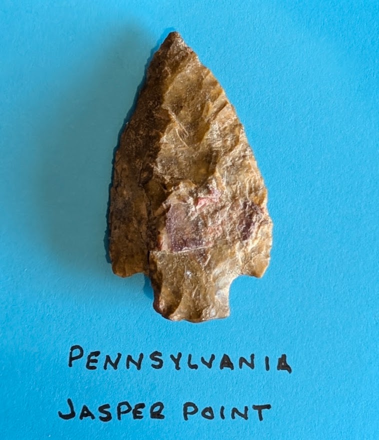 Pennsylvania Jasper Projectile Point prehistoric Native American stone tool with natural patina and bifacial flintknapping on blue background