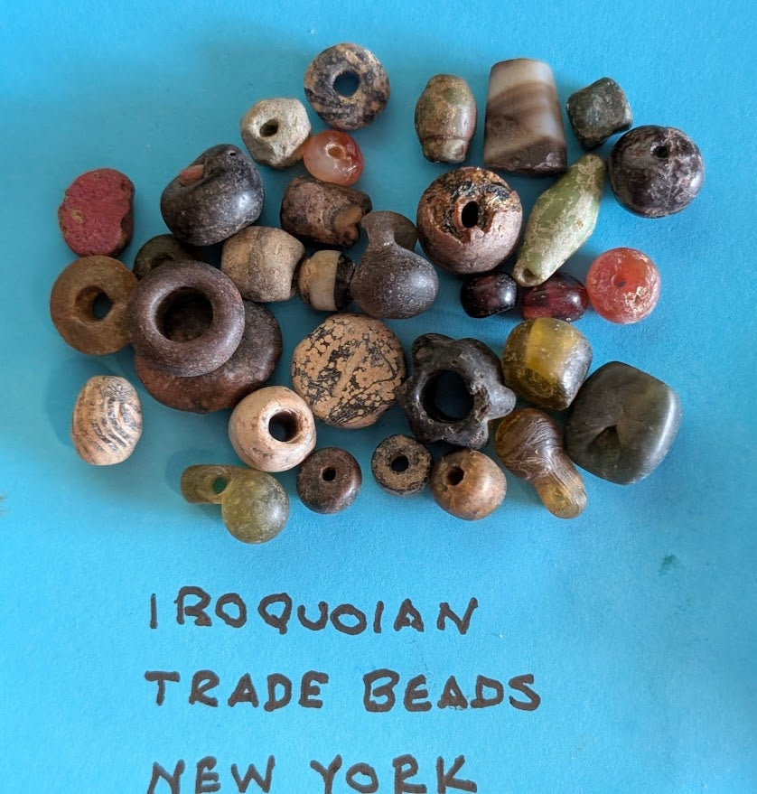 Assortment of authentic Iroquoian trade beads and pendants from New York region on blue background