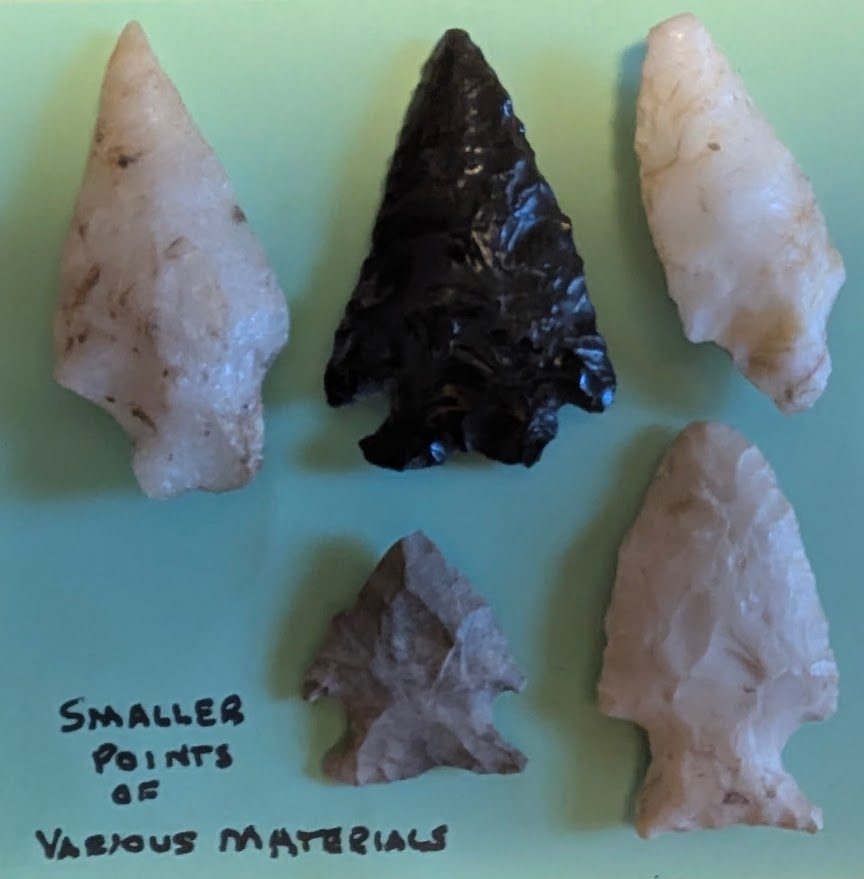 Five Native American projectile points made of quartz, obsidian, and chert with sharp flaking and notched bases