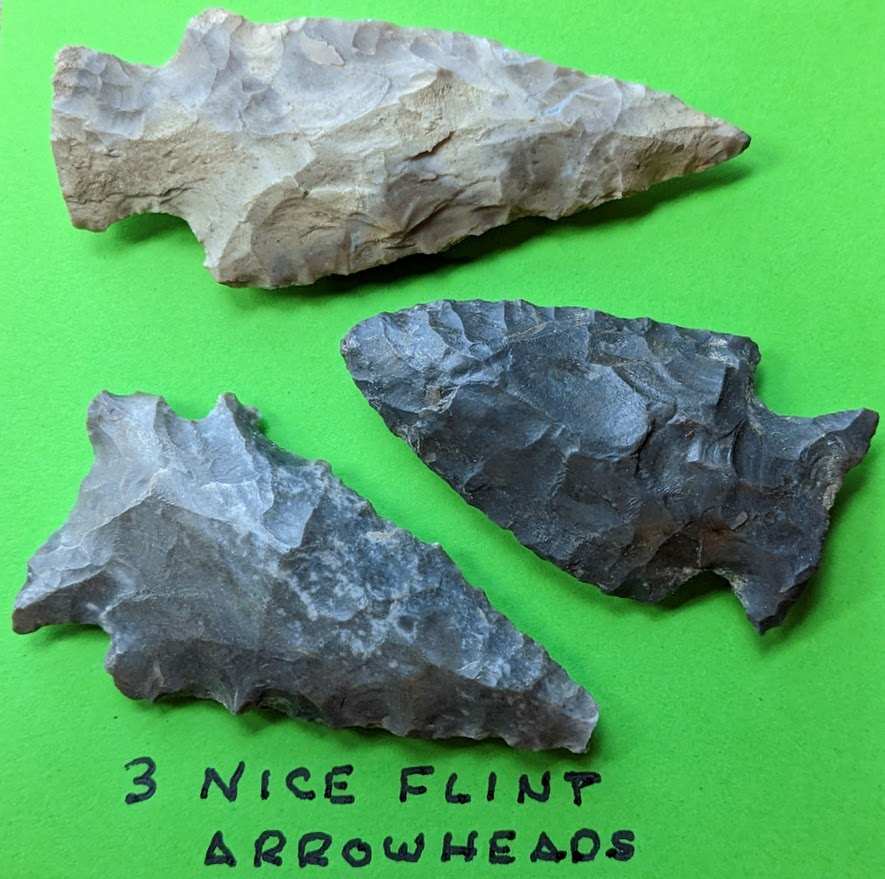 Two Native American arrowheads made of gray and black chert with visible flaking and weathering