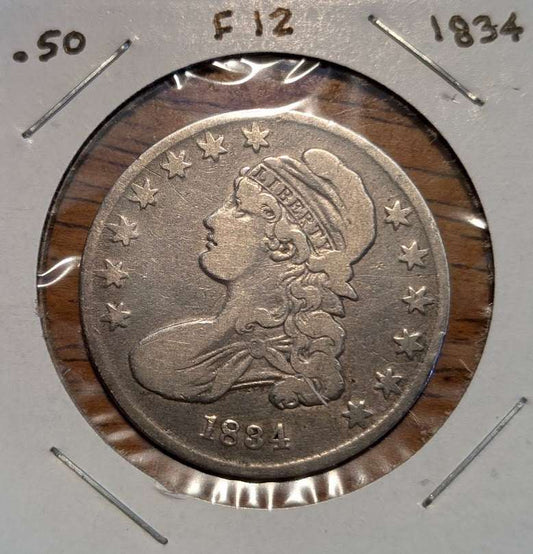 1834 Capped Bust Half Dollar silver coin with a worn, gray-toned surface, Liberty portrait, and surrounding stars in a holder.